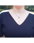 Woman wearing Bow tie Colombian emerald necklace pear cut with high quality natural diamonds, standing outdoors.