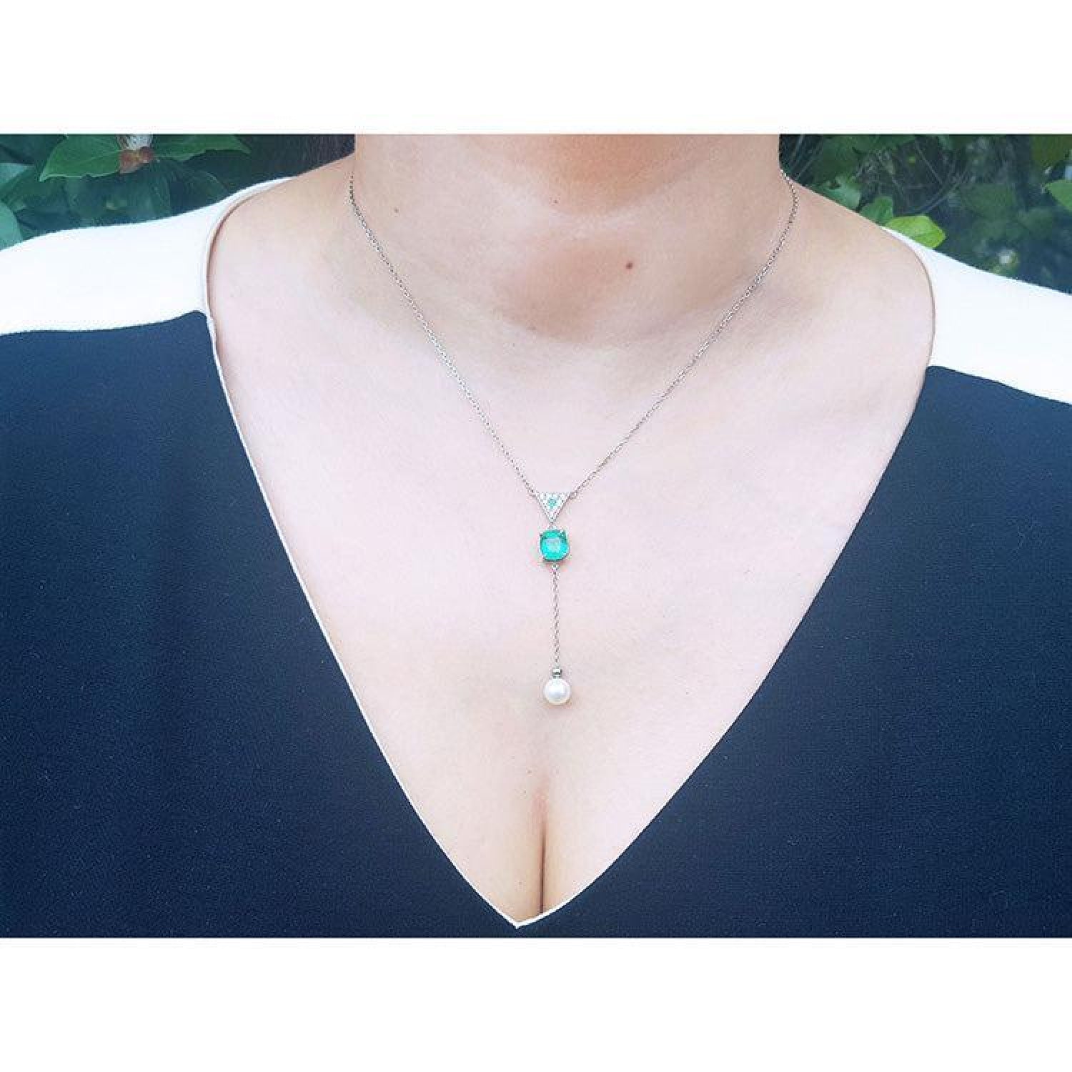 14K white gold necklace with emerald cushion cut pendant, dangling diamond cluster, and white freshwater pearl.