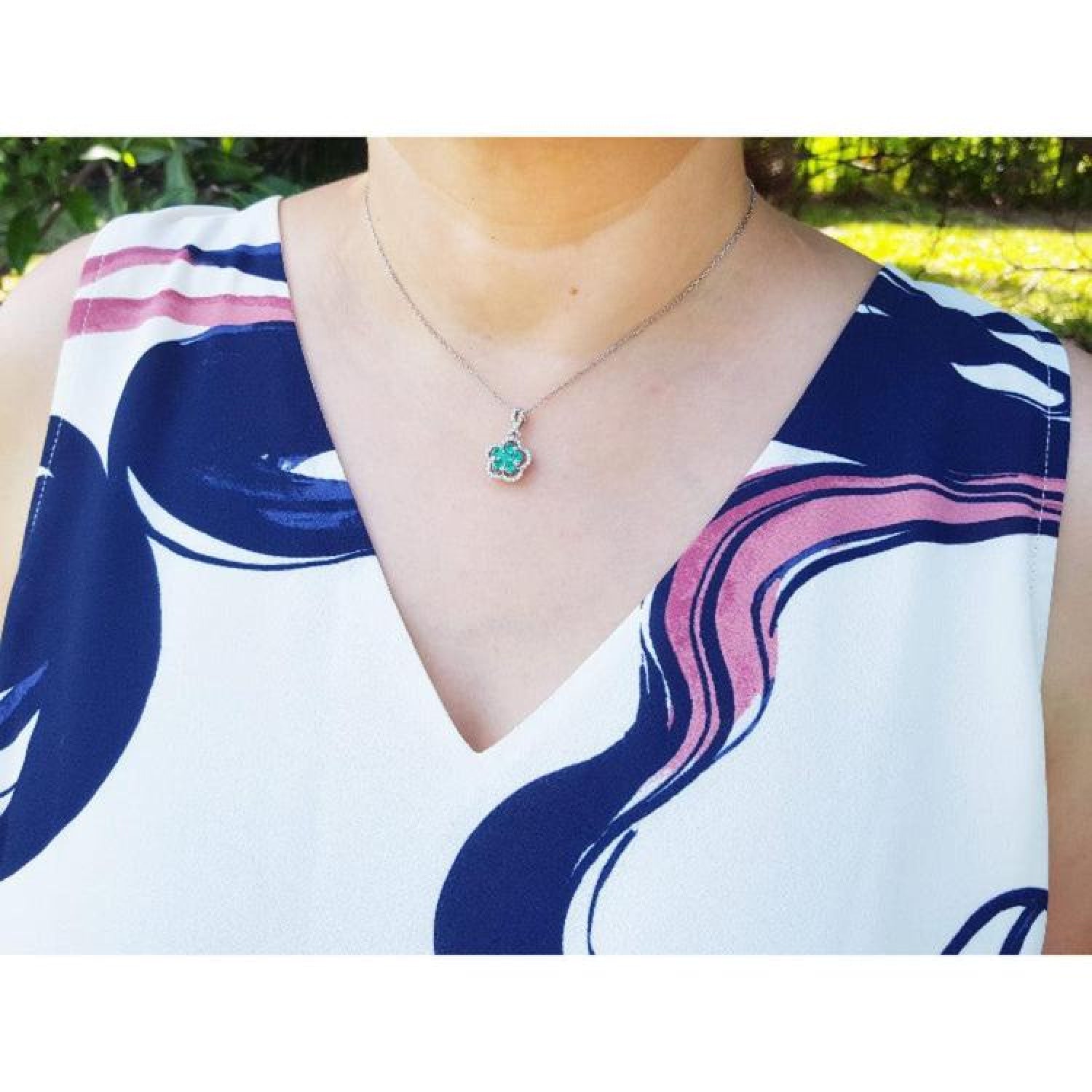 Emerald cluster clover necklace with diamonds on a 14K white gold chain, worn on a person.