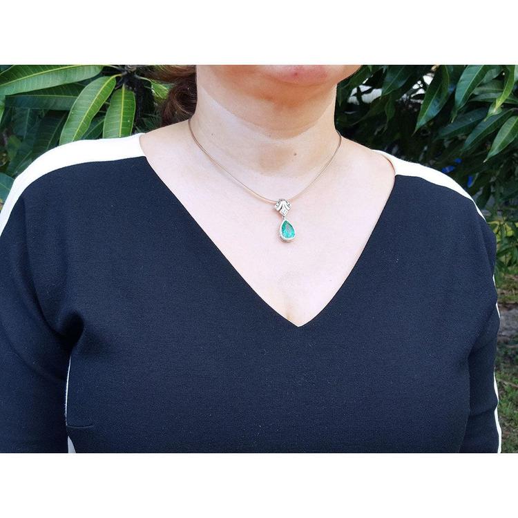 Woman wearing an 18K gold emerald and diamond enhancer necklace with a pear-shaped green emerald.