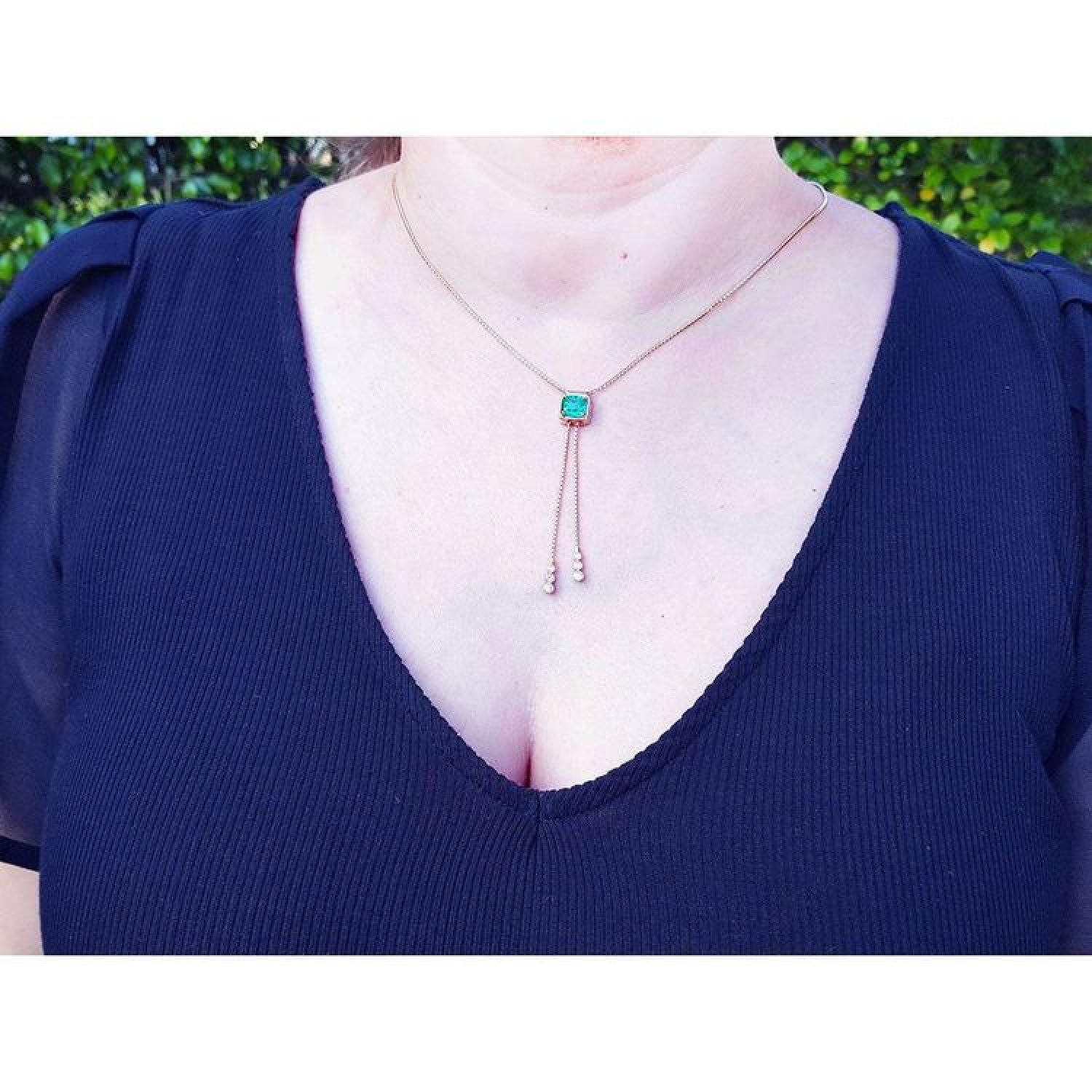 Emerald lariat necklace with an emerald-cut natural emerald, milgrain, prongs, and dangling pearls on a gold box chain.