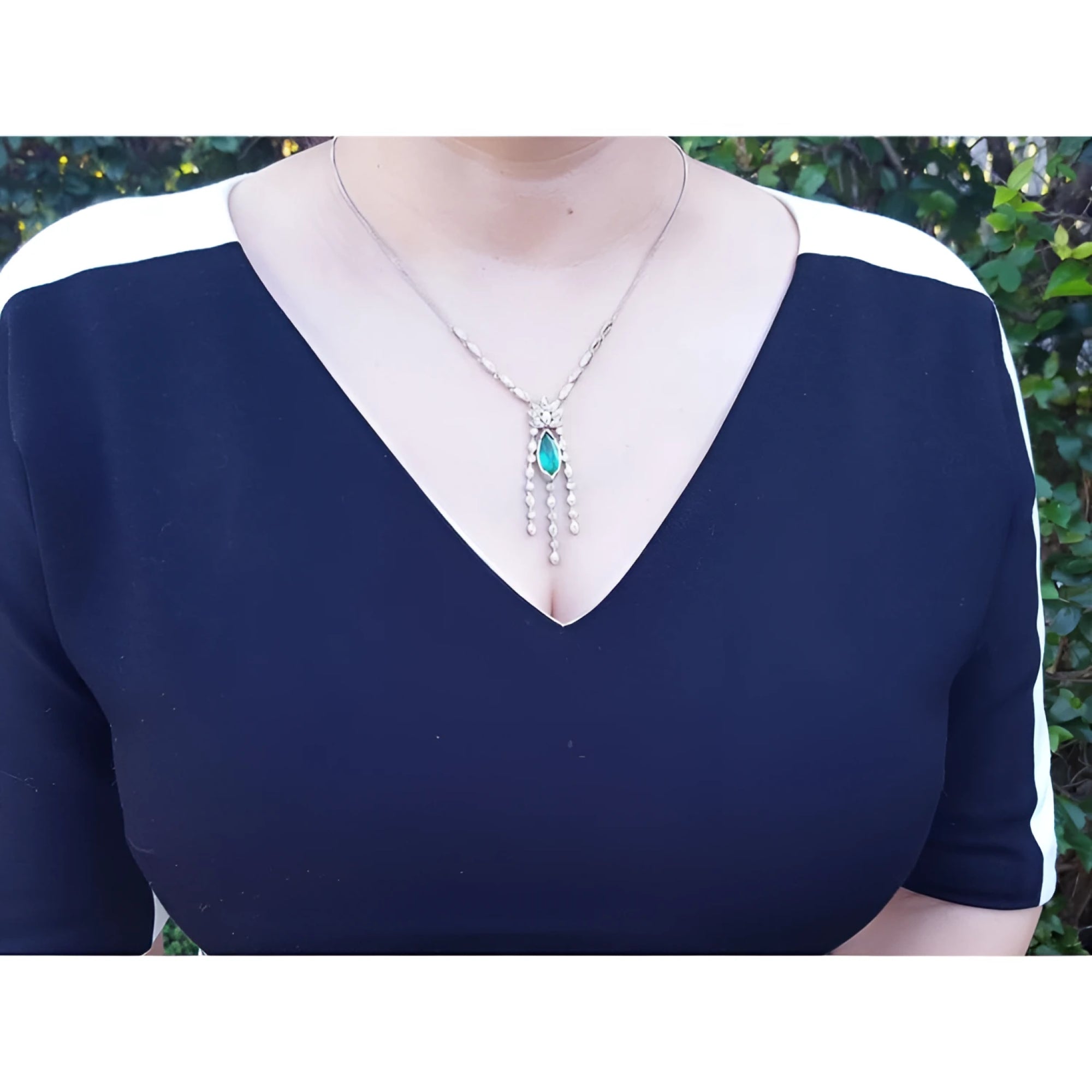 Marquise cut Colombian emerald necklace with diamond links in 14K white gold on a woman's chest.