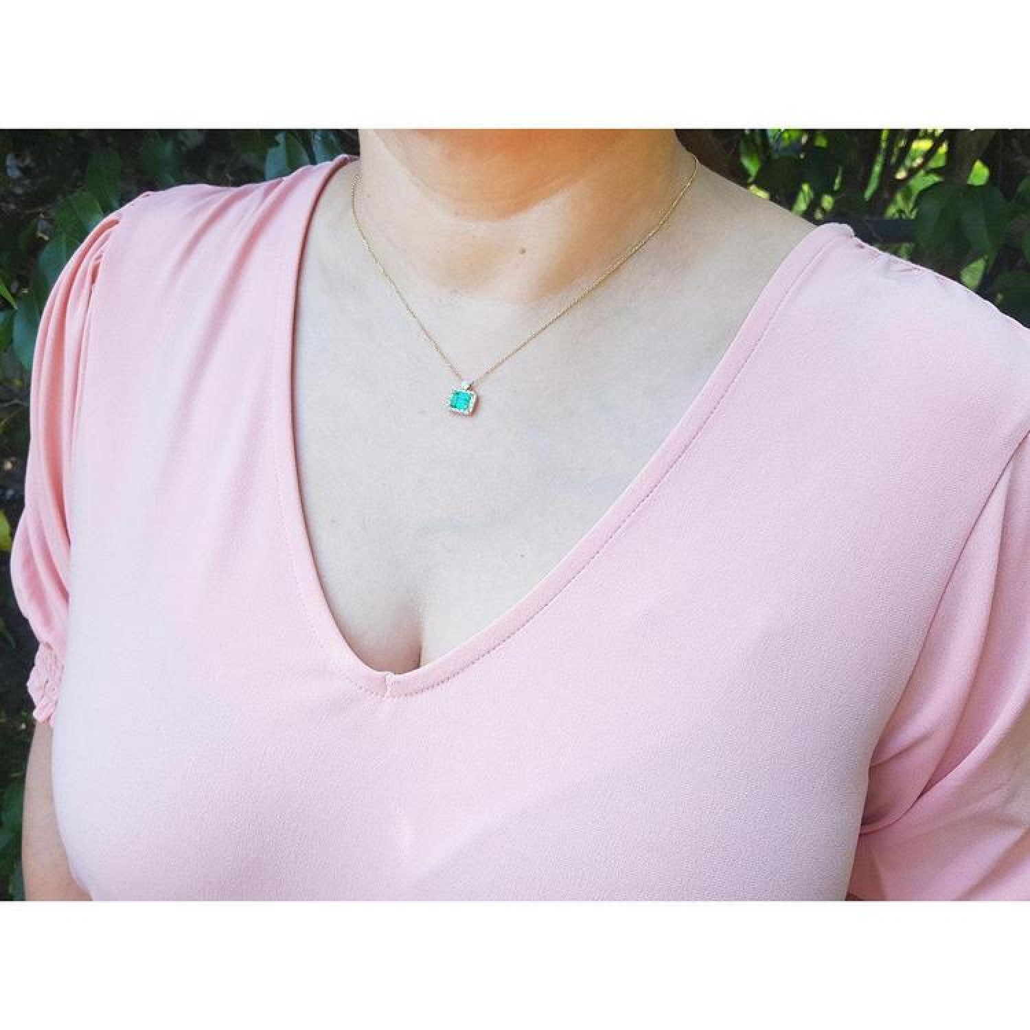 1.31 ct emerald-cut Muzo Colombian emerald necklace with diamonds in 14K yellow gold on a model.