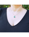 A close-up of a person wearing a 
14K white gold cluster necklace with natural Colombian emeralds and diamonds in a 4-leaf clover design.