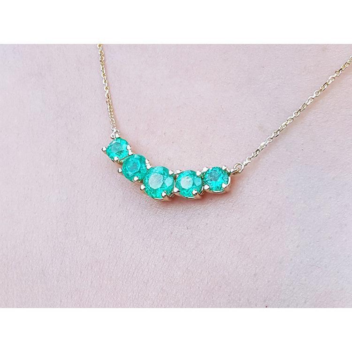 14K gold necklace with five round medium green Colombian emeralds in elegant basket settings.