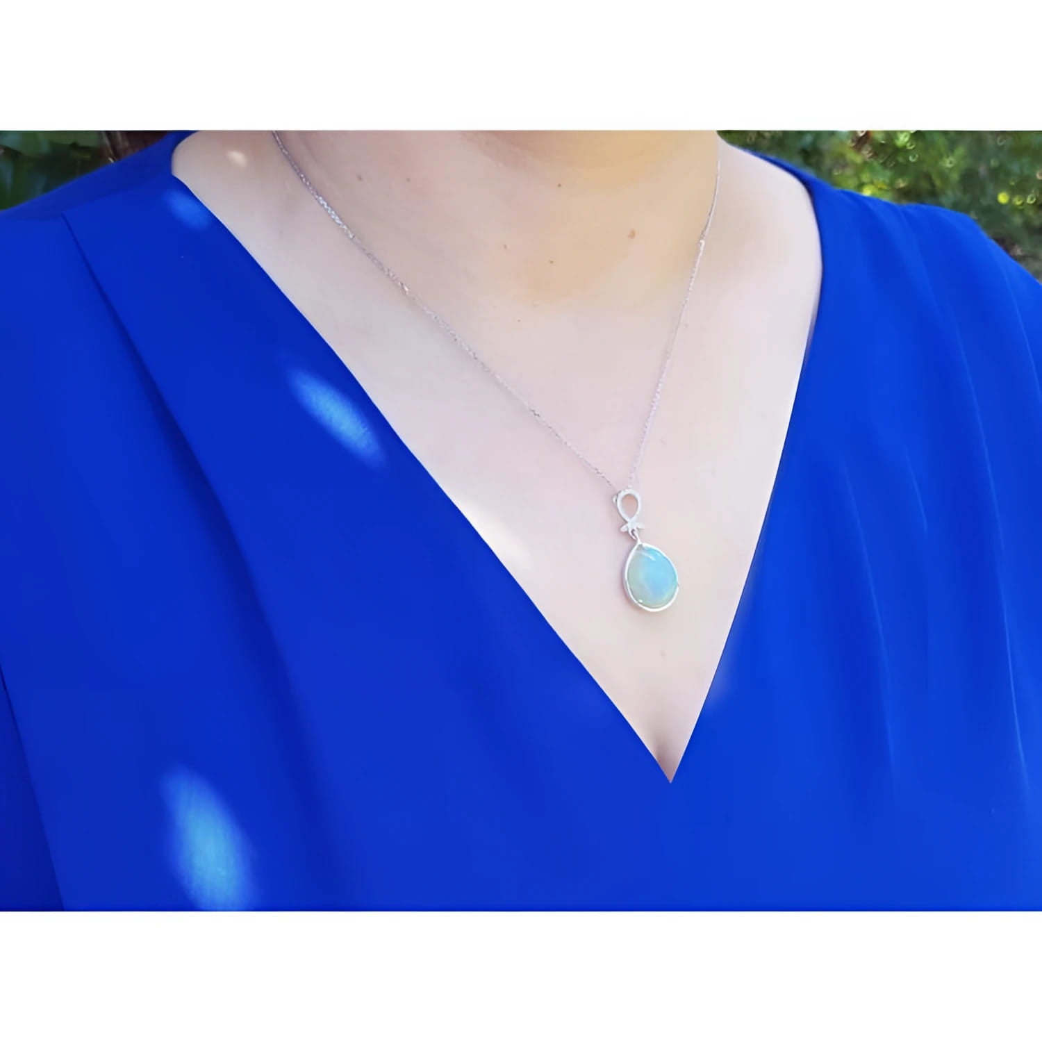 Ethiopian Welo opal and diamond pendant in 14K white gold, worn on a blue top.