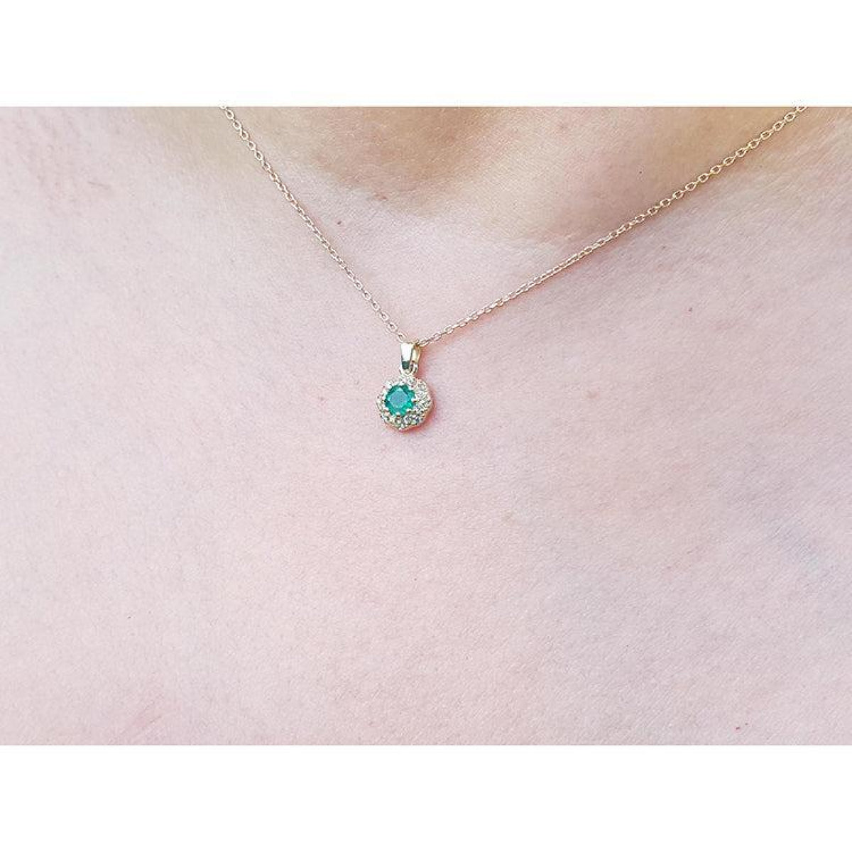 Minimalist 14K yellow gold necklace with a round-cut Colombian emerald pendant surrounded by diamonds.