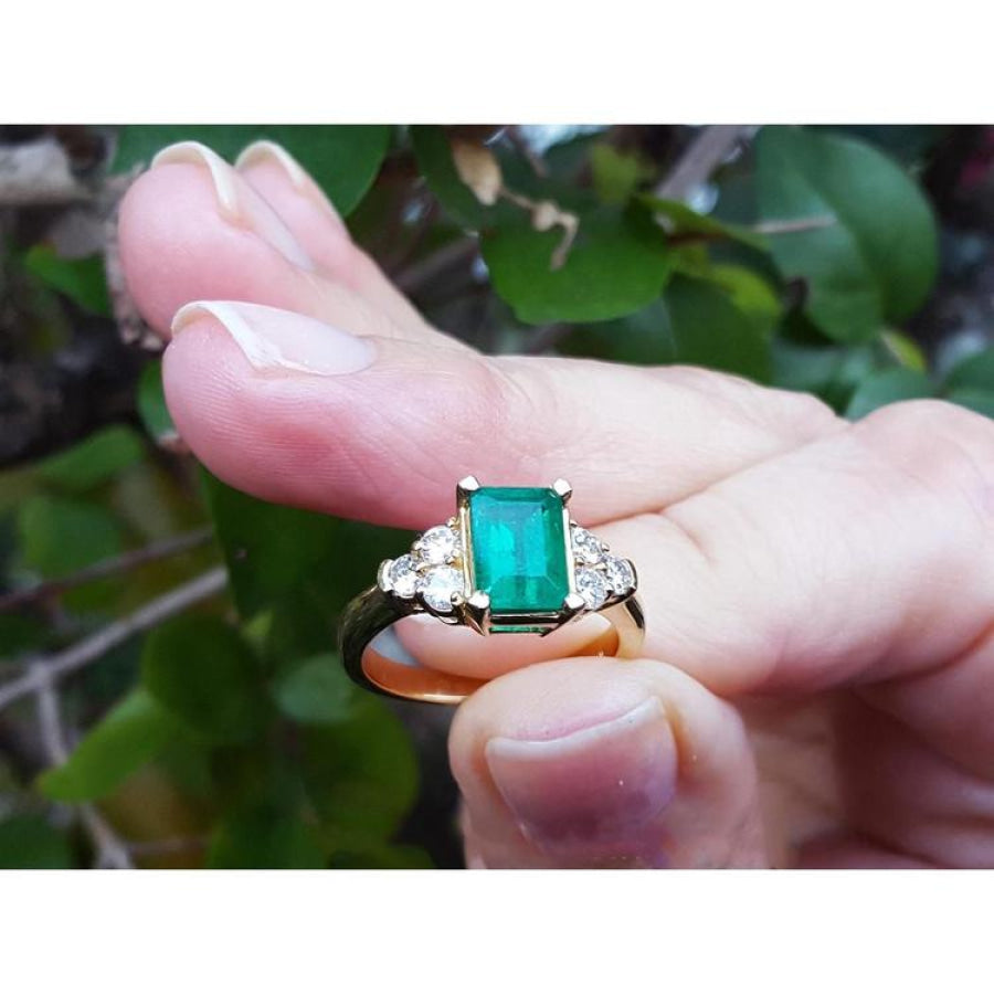 14K yellow gold ring with a rectangular emerald-cut deep bluish-green emerald and six accent diamonds.