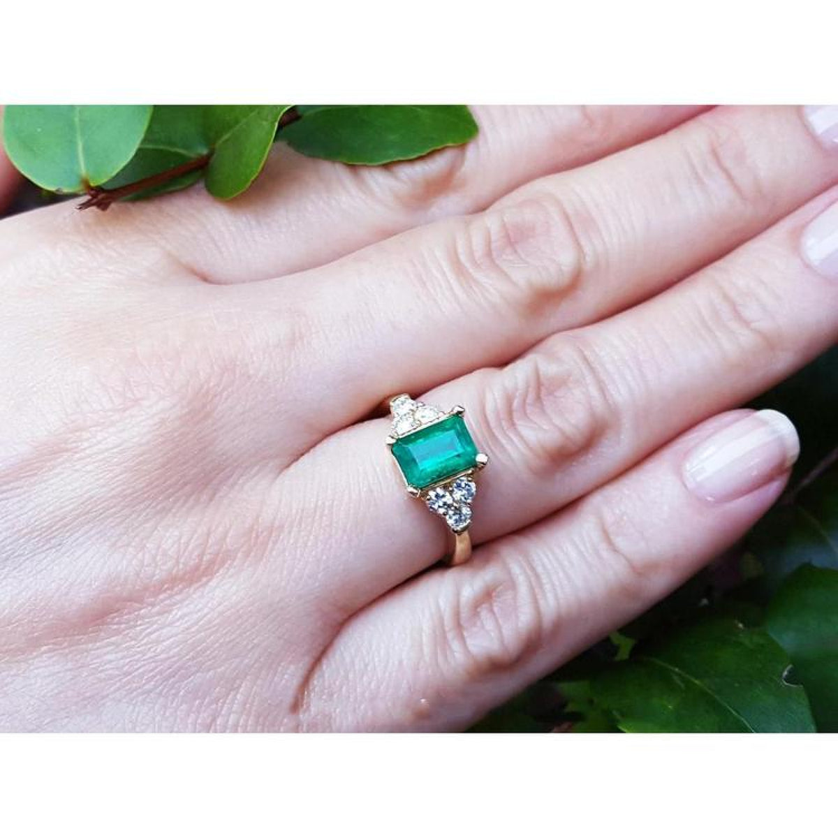 Women's 14K yellow gold ring with a rectangular emerald and three accent diamonds on each side.