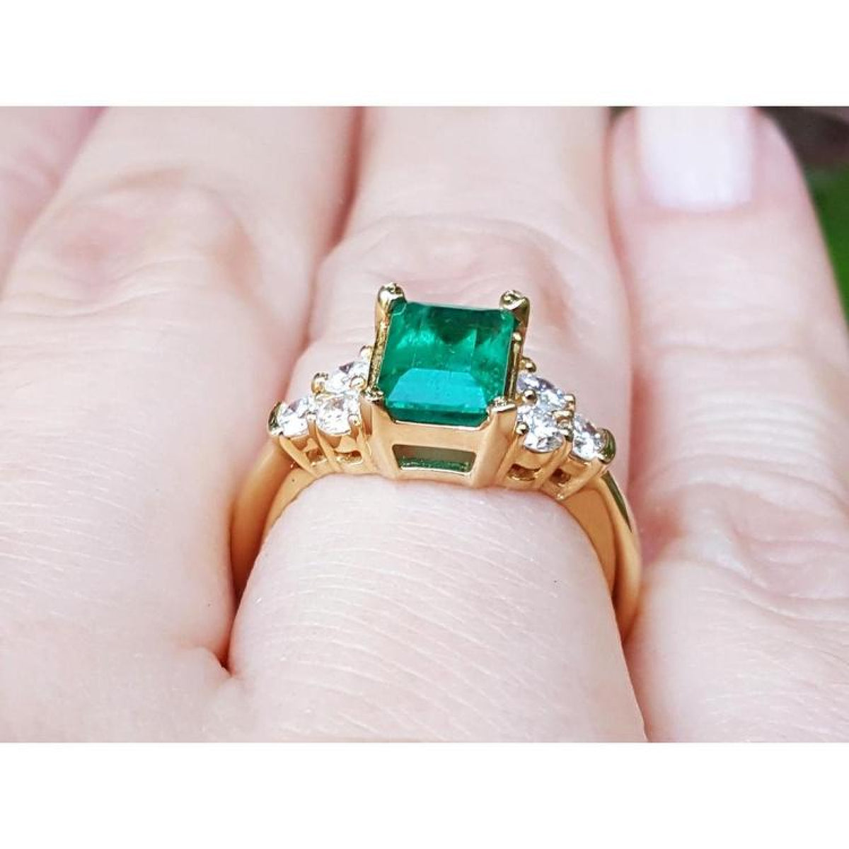 Women's 14K yellow gold ring with a rectangular emerald-cut deep bluish-green emerald and six accent diamonds.