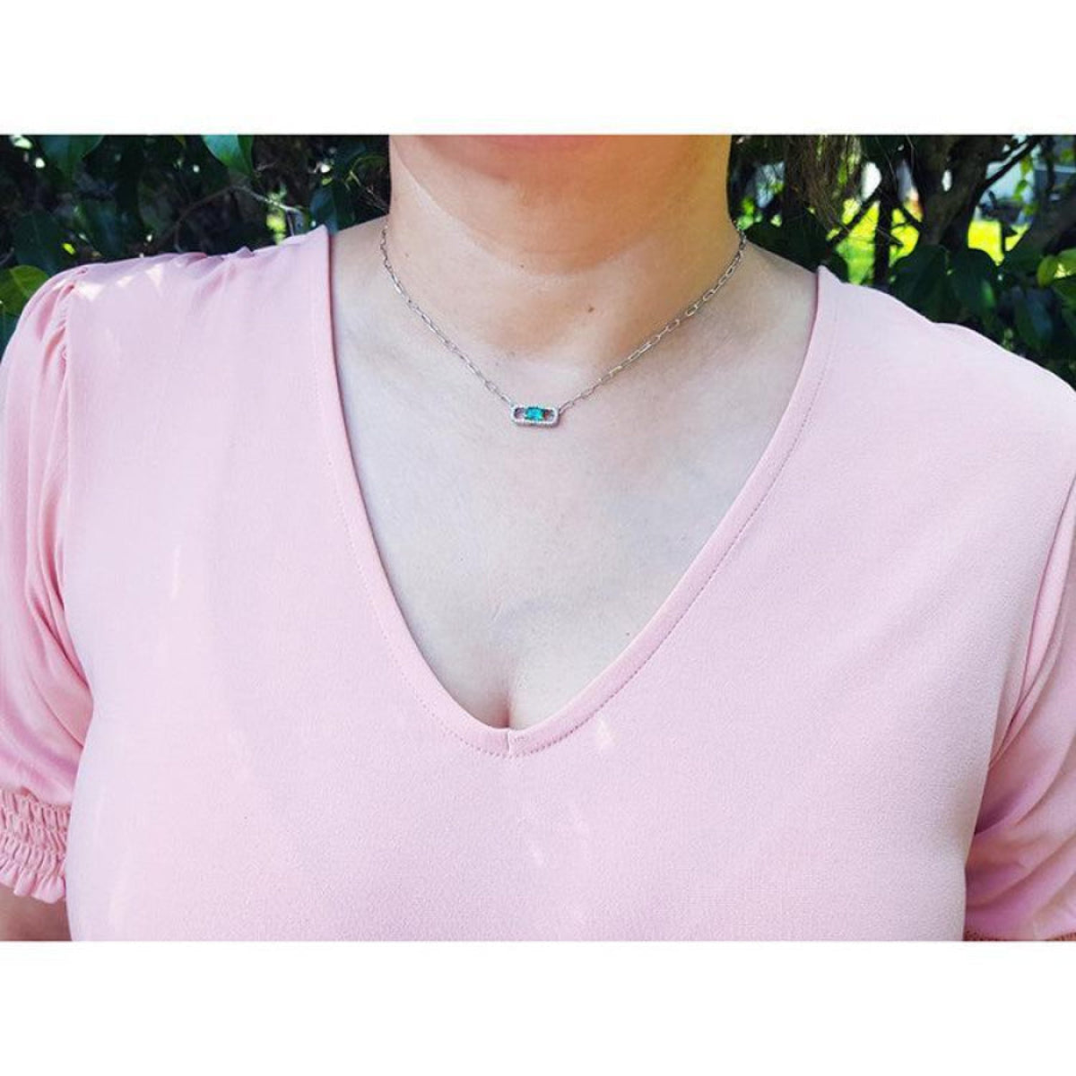 0.68 ct Colombian emerald and diamond paper clip necklace in 18K white gold on a model.