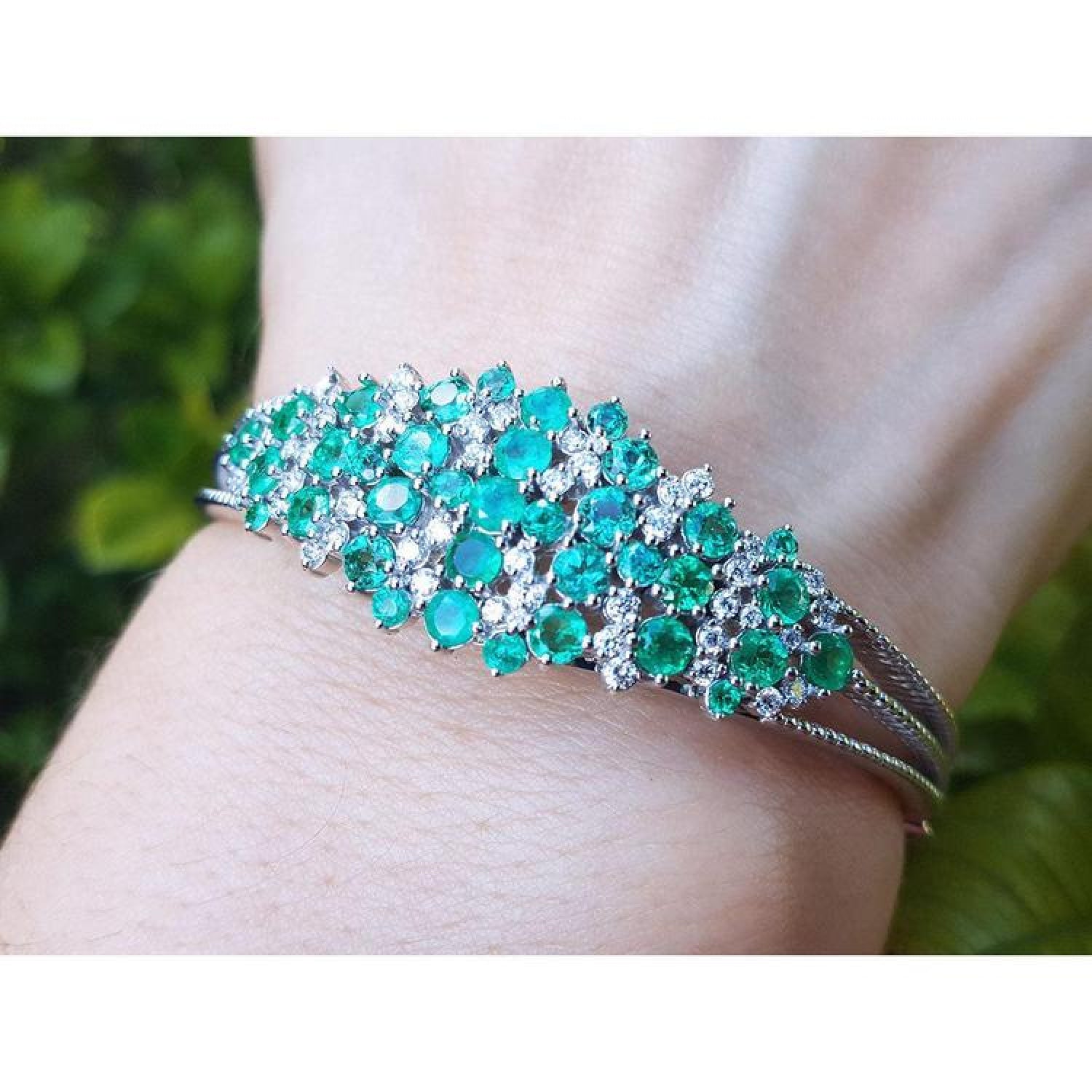 14k white gold bangle bracelet with round Colombian emeralds and diamonds.