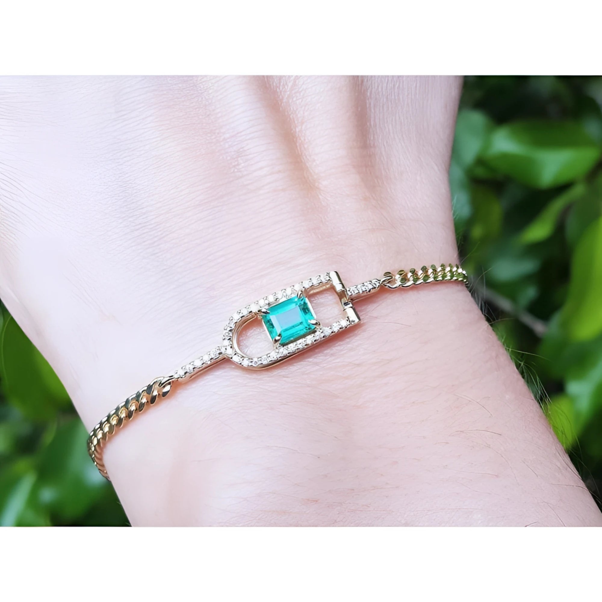 14K yellow gold bracelet with a square emerald-cut Colombian emerald and diamond accents on a wrist.
