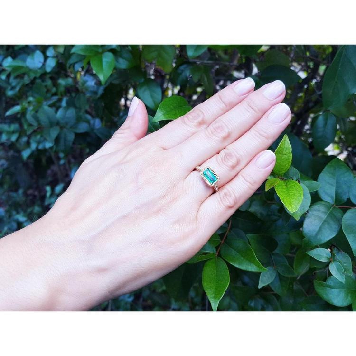 1.30 carat emerald-cut Colombian emerald ring in 14K yellow gold, east-west style, on a hand.