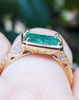 The underside view of a colombian emerald ring in yellow gold on a finger.