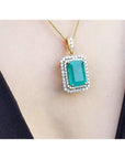 Gold necklace with a natural emerald into a double halo diamond pendant on a person's neck.