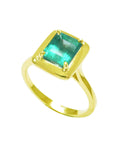 The tilted position of this emerald solitaire ring shows the top gemstone encased in wide bezels and shank profile.