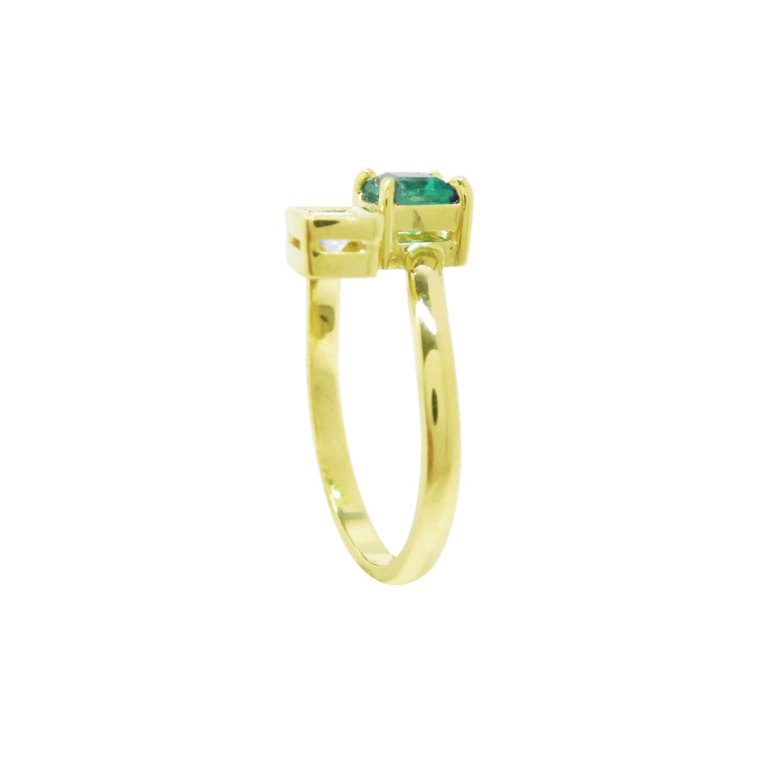 A yellow gold toi et moi emerald and diamond ring in a prong setting, with a small clear accent stone on each side.