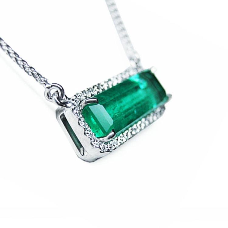 zoom-in view of a 18k white gold elongated emerald necklace east west orientation halo diamonds